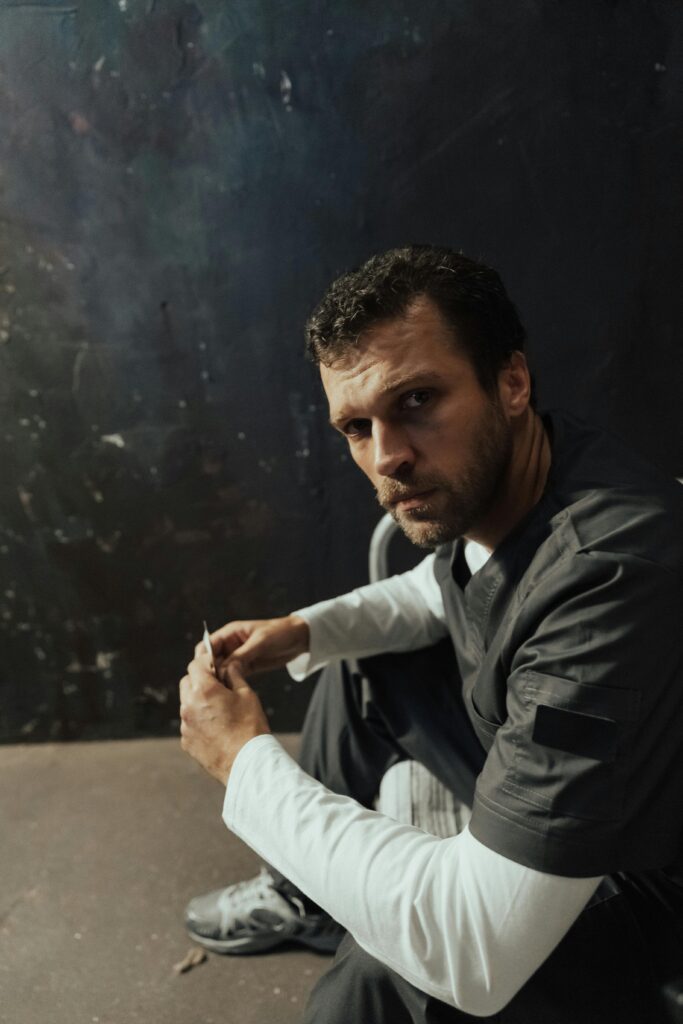 A man in a prison uniform seated indoors, looking serious and contemplative.